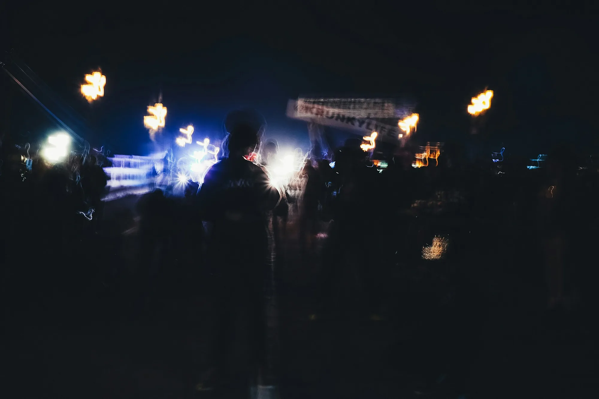 Silhouetted guests moving through abstract stage lights at night