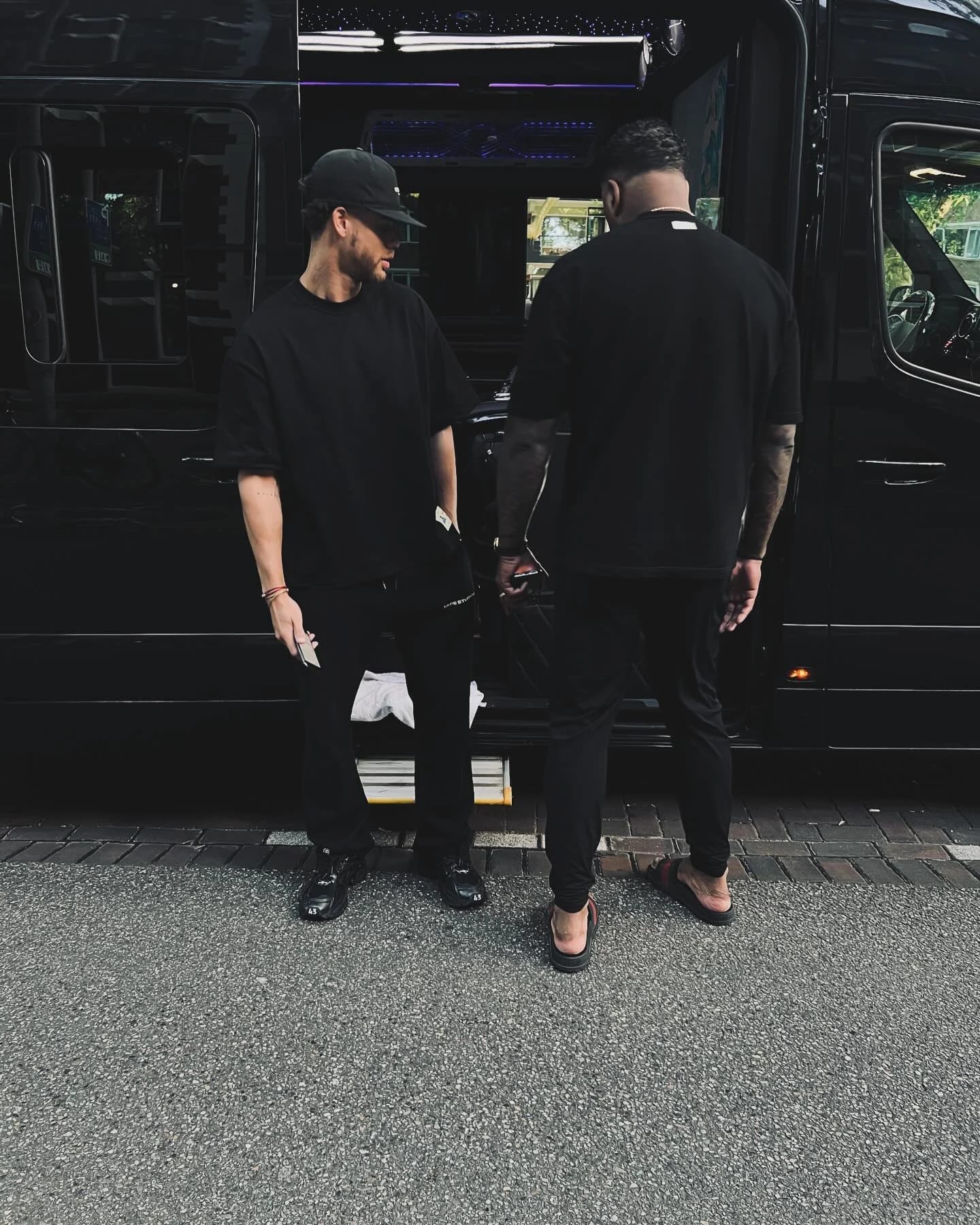 Two people beside the open door of a black vehicle